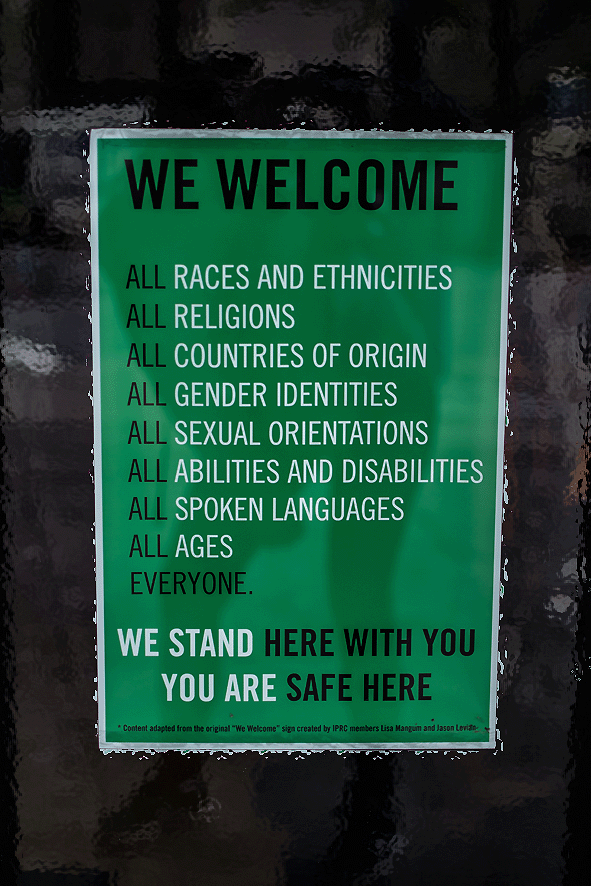 Cartello su sfondo verde con la scritta “We welcome all races and ethnicies, all religions, all countries of origin, all gender identities, all sexsual orientations, all abilities and disabilities, all spoken languages, all ages everyone. We stand here with you, You are safe here.