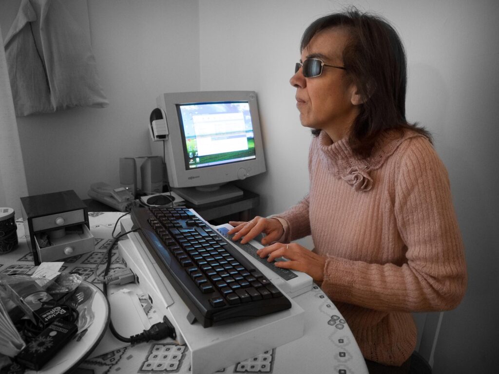 Donna cieca che lavora al computer con display Braille