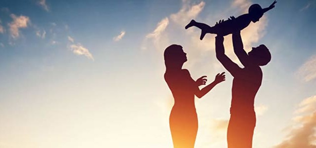 il profilo di due genitori che fanno giocare un bambino con il cielo azzurro sullo sfondo