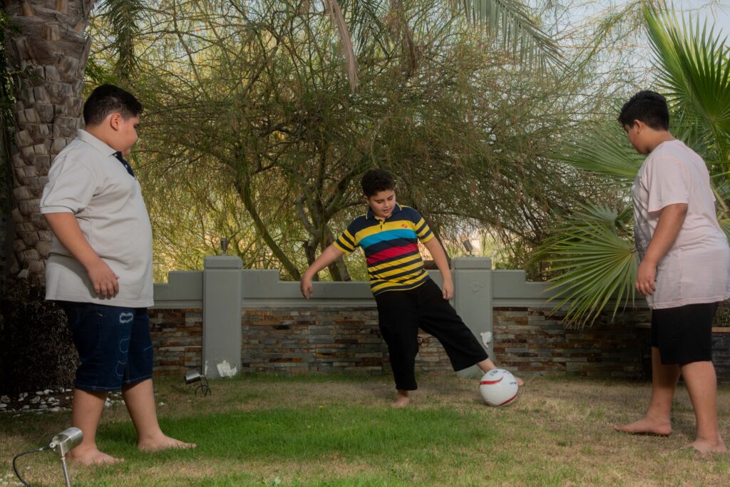 tre ragazzi sovrappeso che giocano a calcio