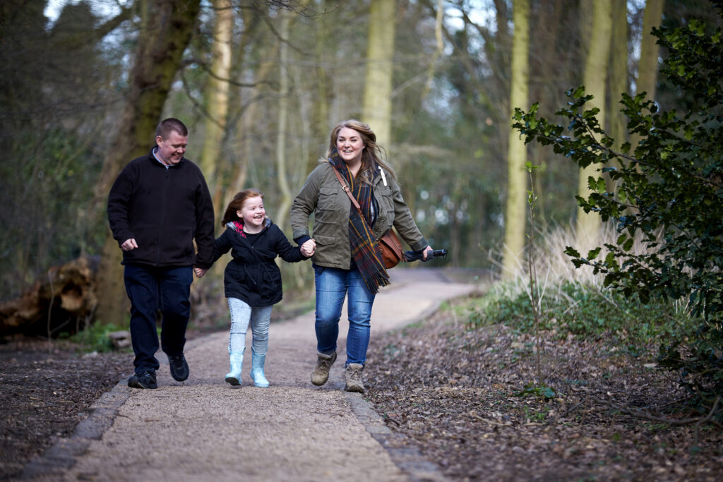 Famiglia con entrambi i genitori e la figlia un po' sovrappeso che passeggiano sorridenti nel bosco