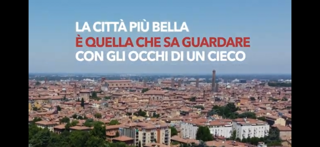 Panoramica di Bologna con la scritta "La cittè più bella è quella che sa guardare con gli occhi di un cieco"