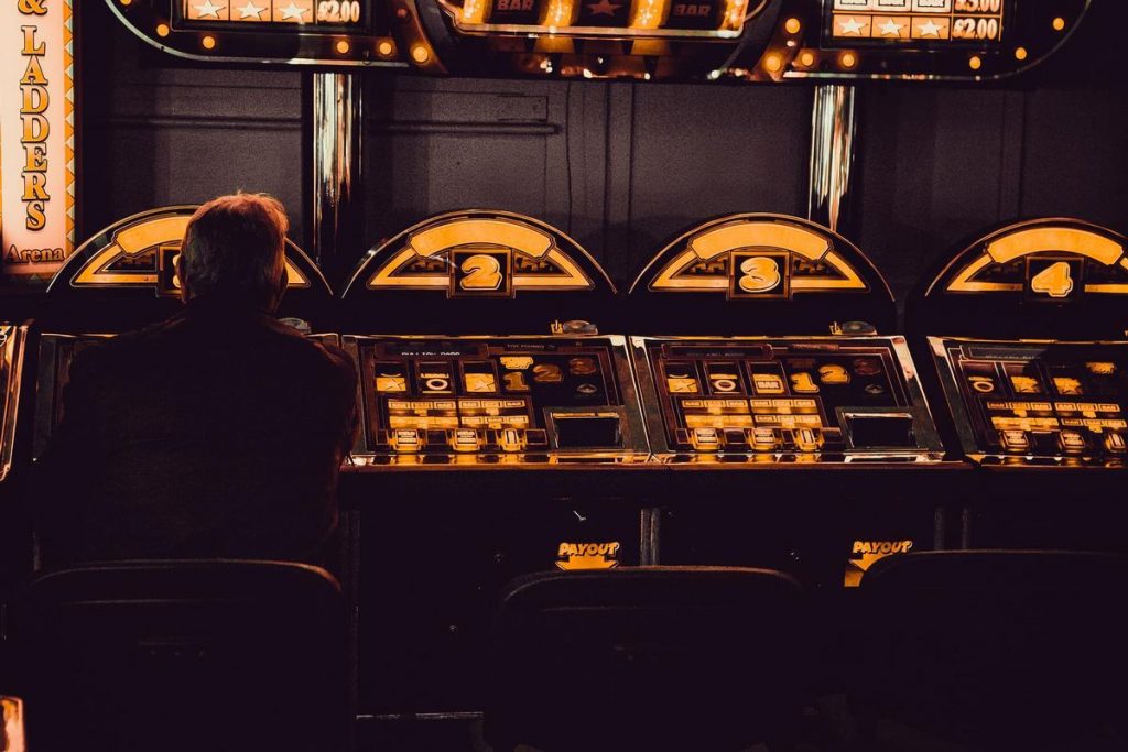 Un giocatore davanti alle slot di un casinò (Carl Raw - Unsplash)