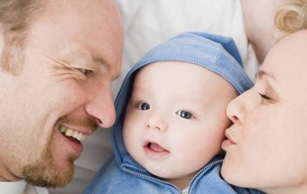 Immagine di un neonato coccolato tra i due genitori